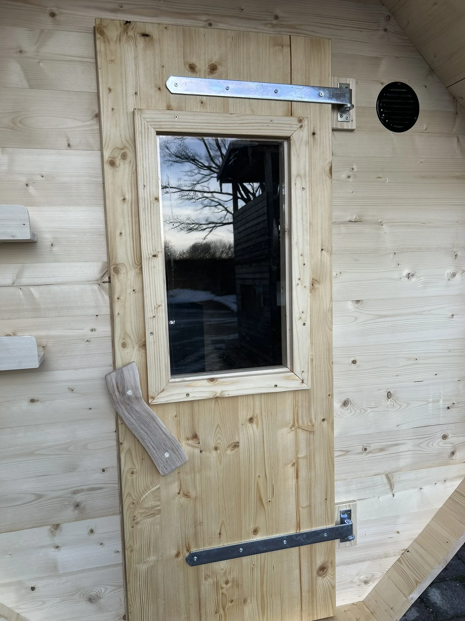 Holztür der Fasssauna mit Griff und Glasfenster