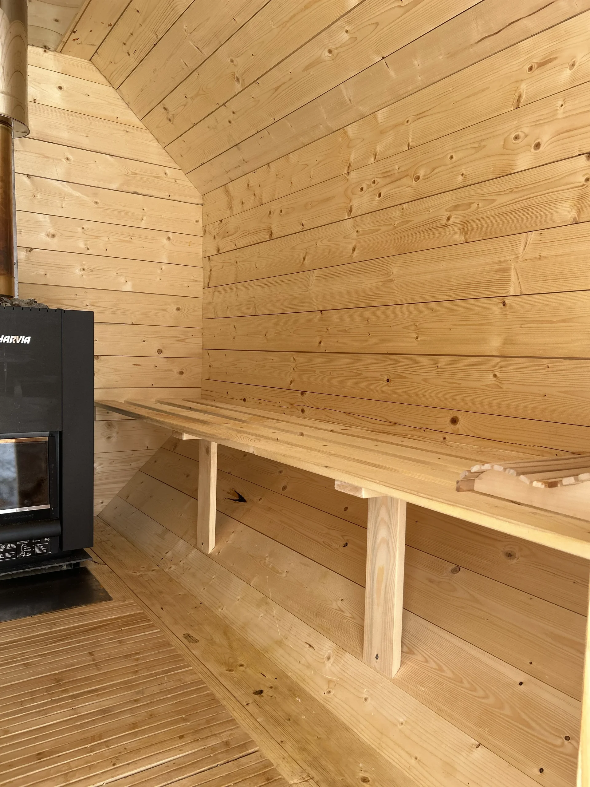 Innenraum des Mangfallfass mit Blick auf Ofen und Sitzbank aus Holz