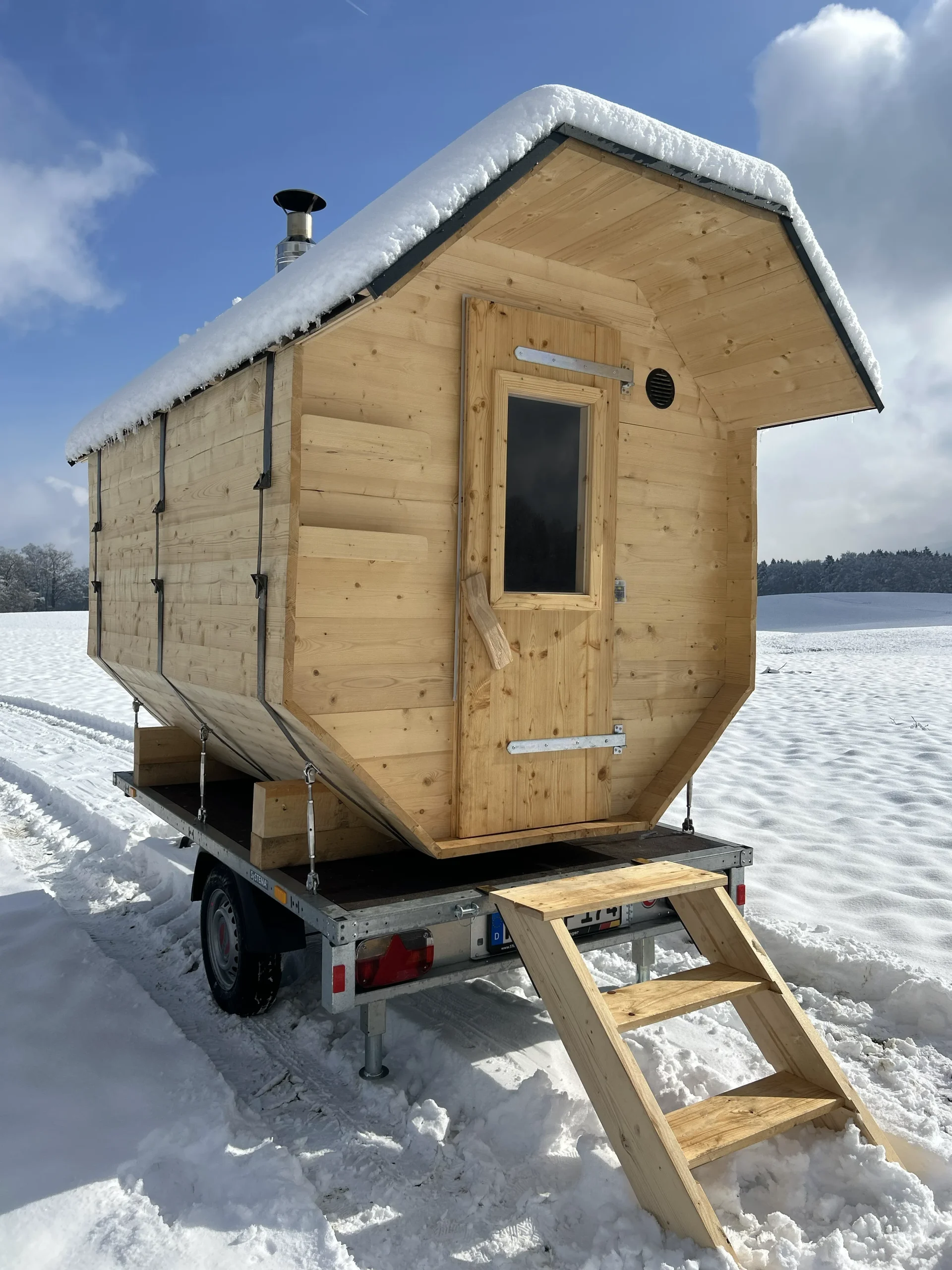 Schneebedeckte Fasssauna auf Anhänger im Winter